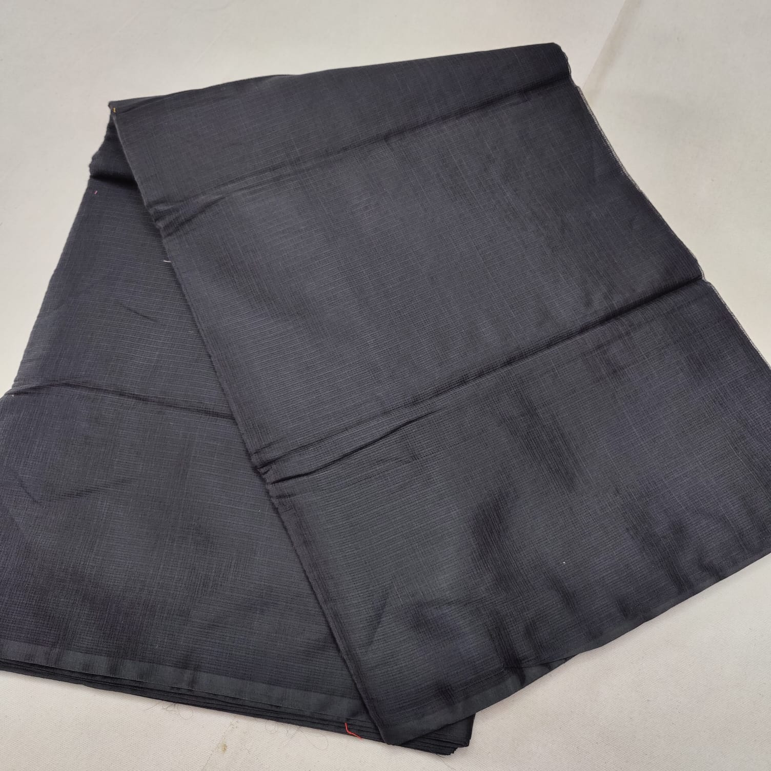 A folded blue Kota cotton plain saree with a solid pattern, displayed on a white background.