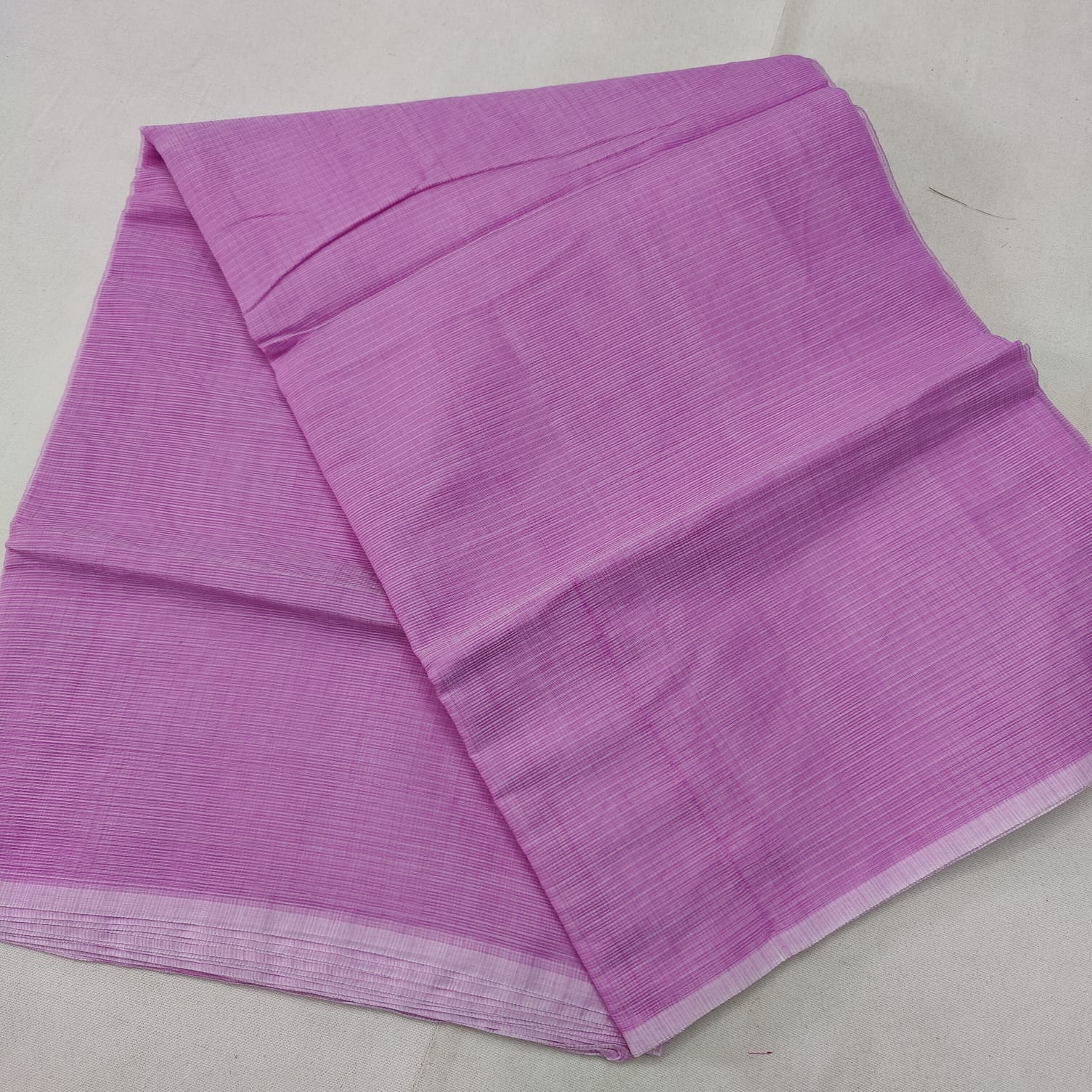 A folded blue Kota cotton plain saree with a solid pattern, displayed on a white background.