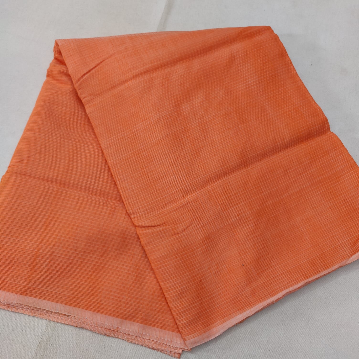 A folded blue Kota cotton plain saree with a solid pattern, displayed on a white background.