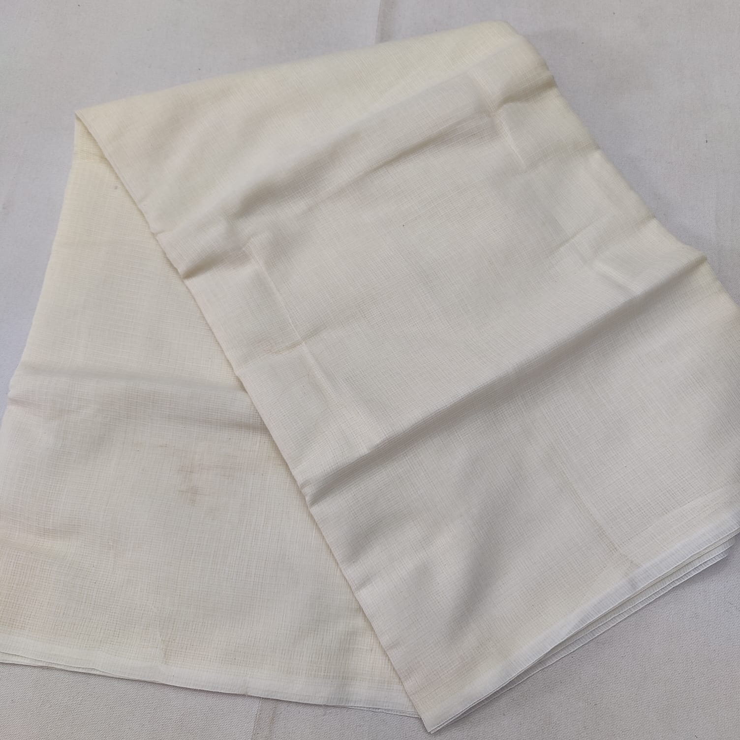 A folded blue Kota cotton plain saree with a solid pattern, displayed on a white background.