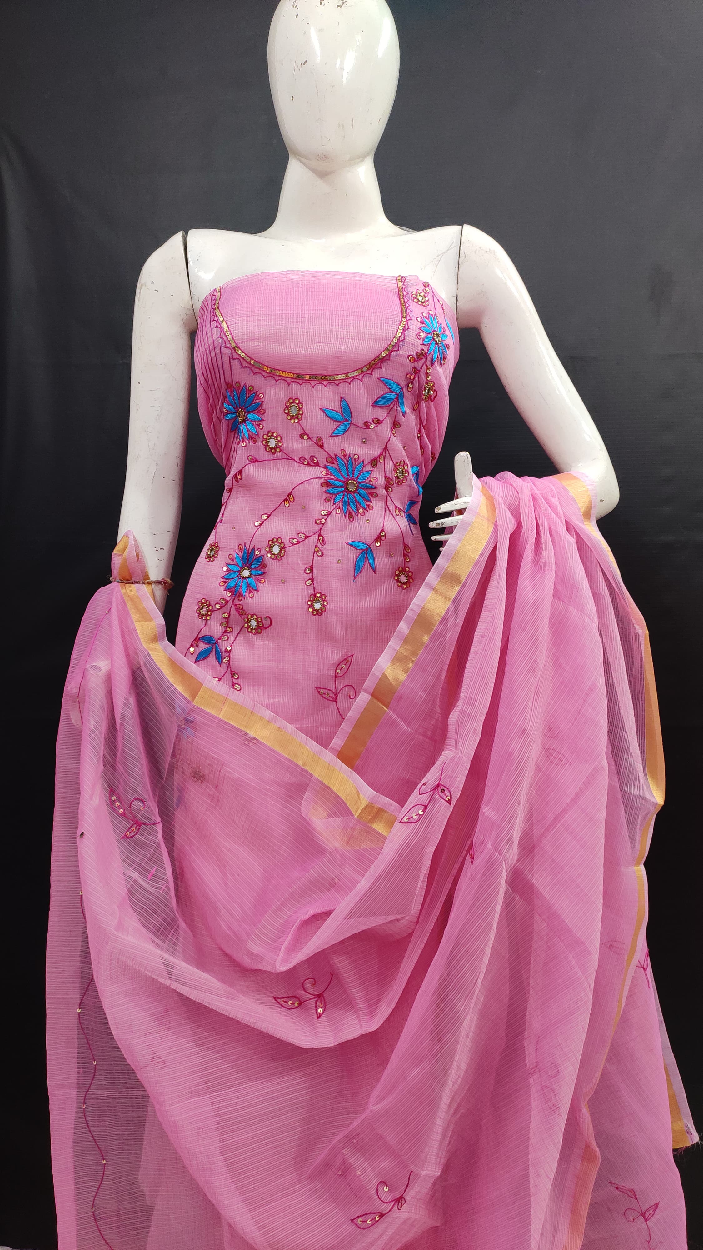Mannequin wearing a pink saree with floral embellishments on a black background
