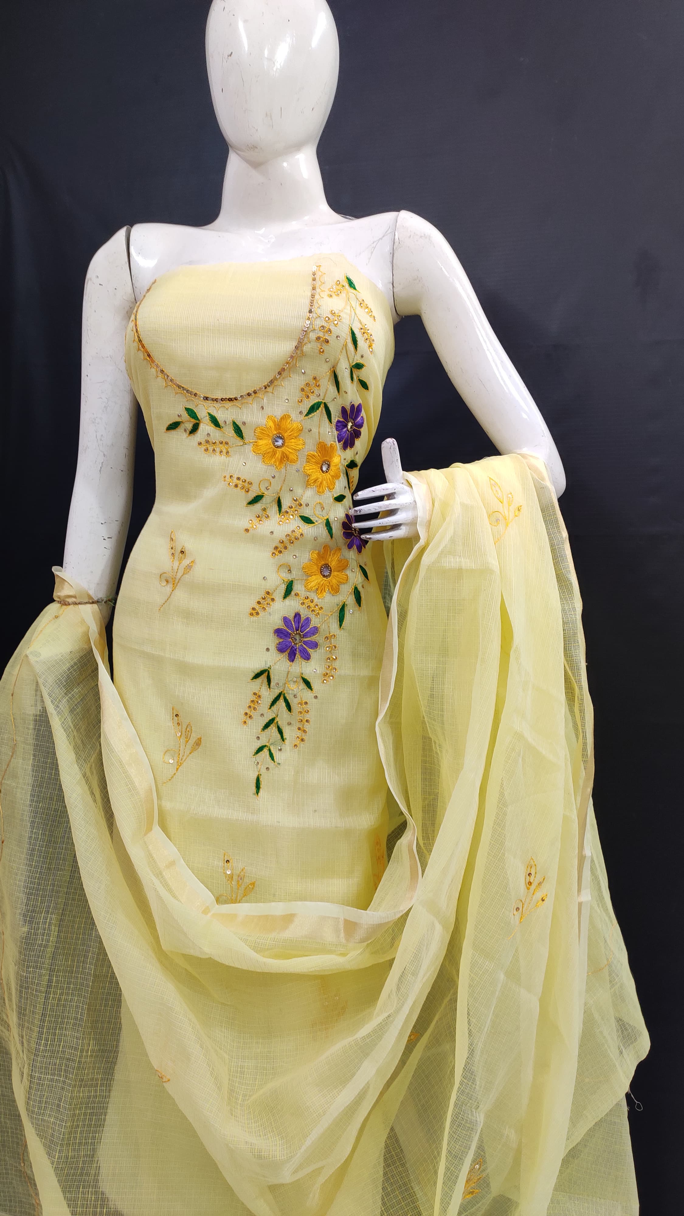 Mannequin wearing a light yellow embroidered dress with a dupatta on a dark background