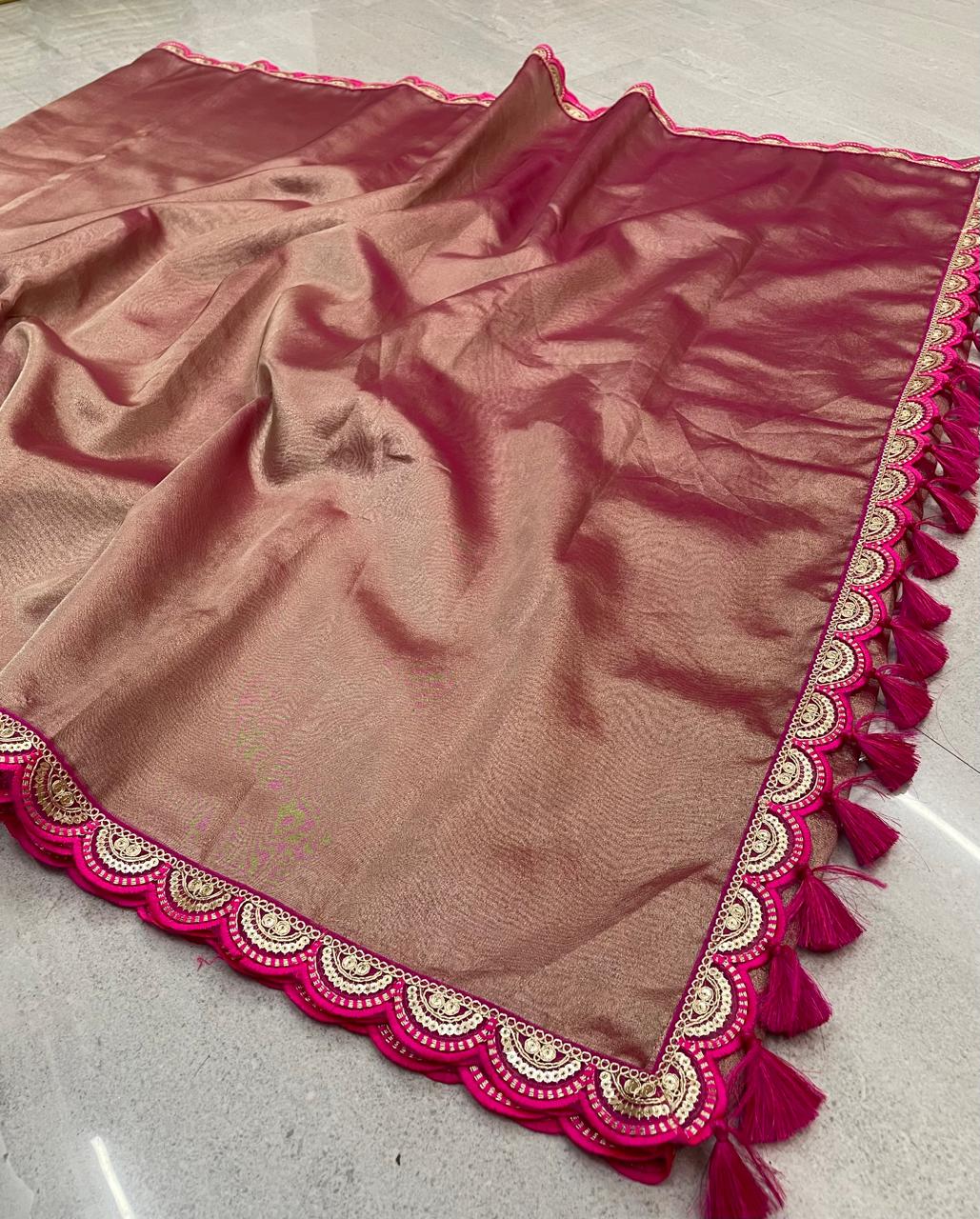 Brown fabric with pink border and tassels on a light gray surface