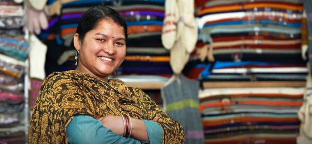 Smiling textile shop owner with stacks of fabric