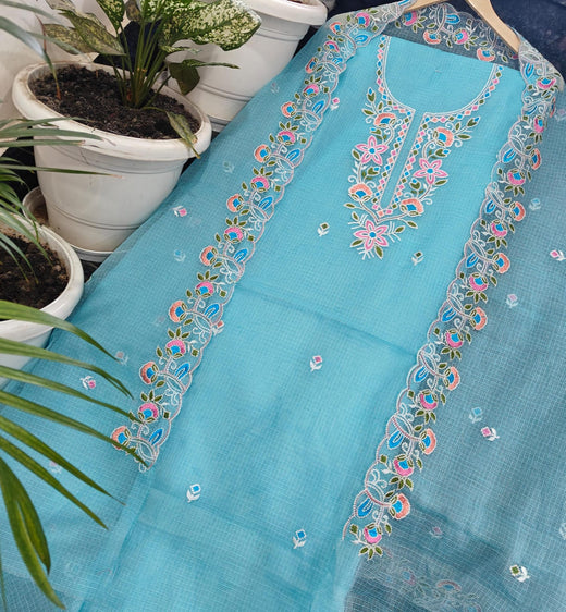 Kota Doria fabric with floral embroidery on a surface with potted plants in the background