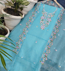 Kota Doria fabric with floral embroidery on a surface with potted plants in the background