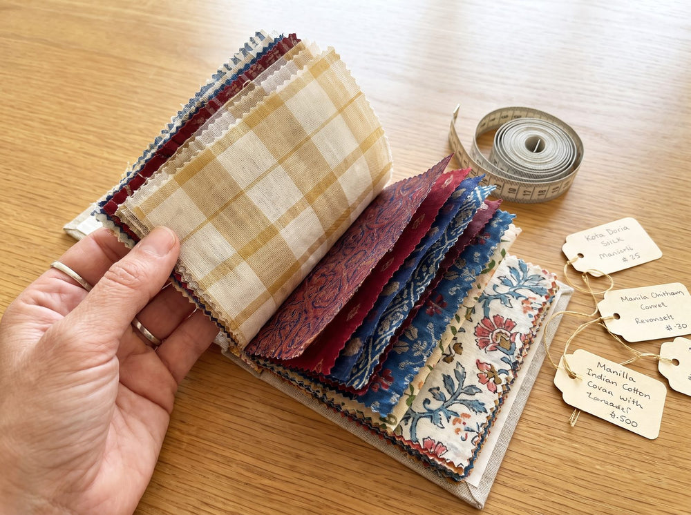 Hand holding a swatch book of saree fabric samples